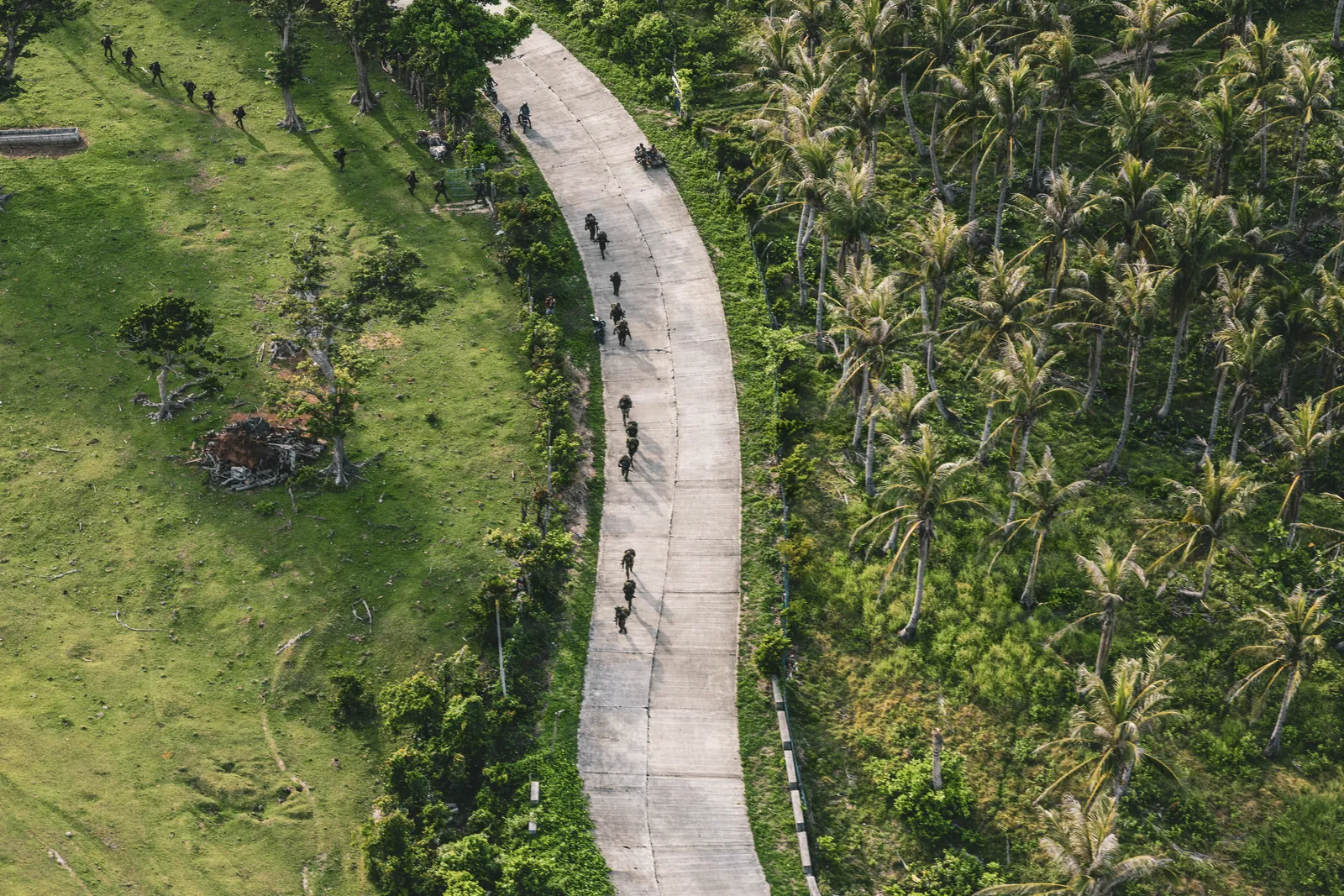 Personnel moving through tropical terrain during field operations.