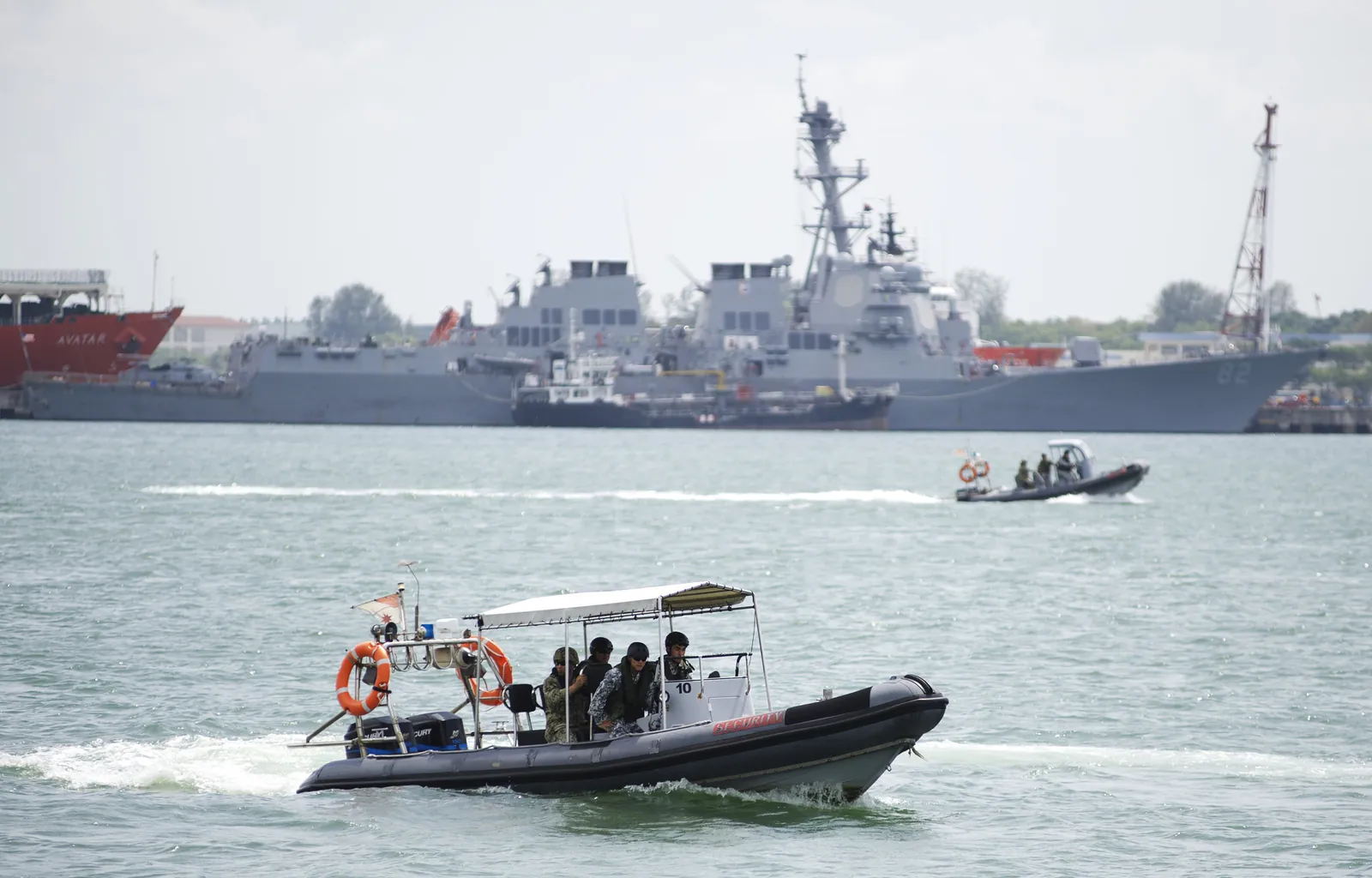 Rigid-hull inflatable boat operating in Singapore waters near naval vessels.